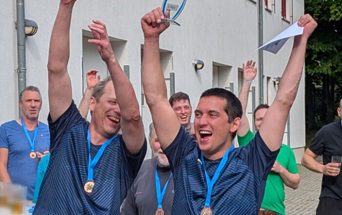Zwei Männer halten einen Pokal hoch und jubeln
