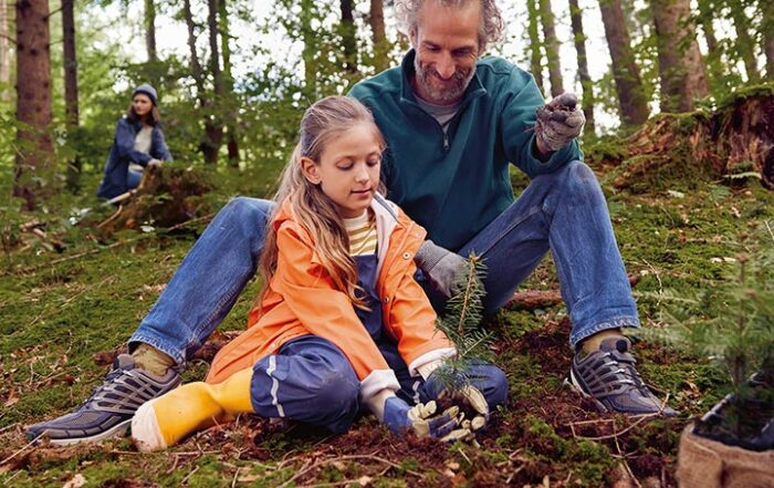 Kind mit Opa im Wald beim Baumpflanzen