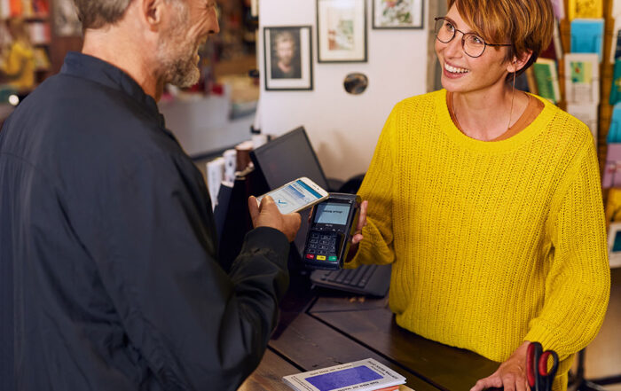 Mann bezahlt mobil mit seinem Handy in einer Buchhandlung