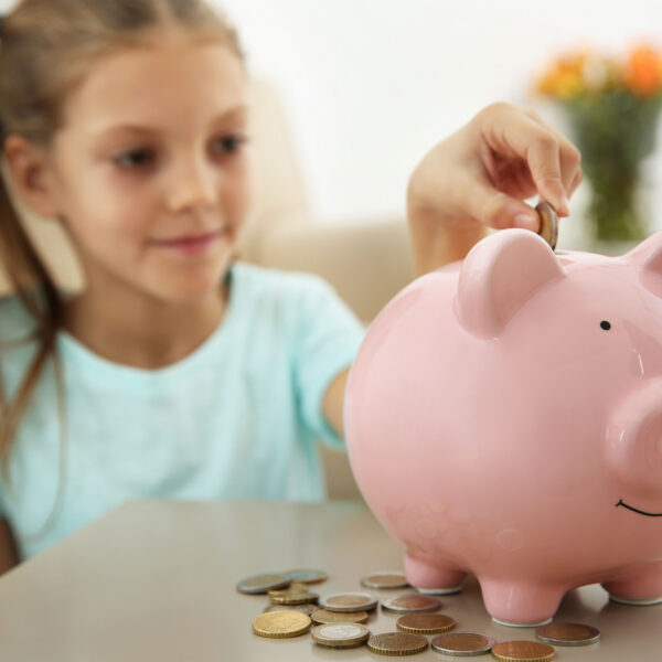 Kind wirft Geld in eine Spardose