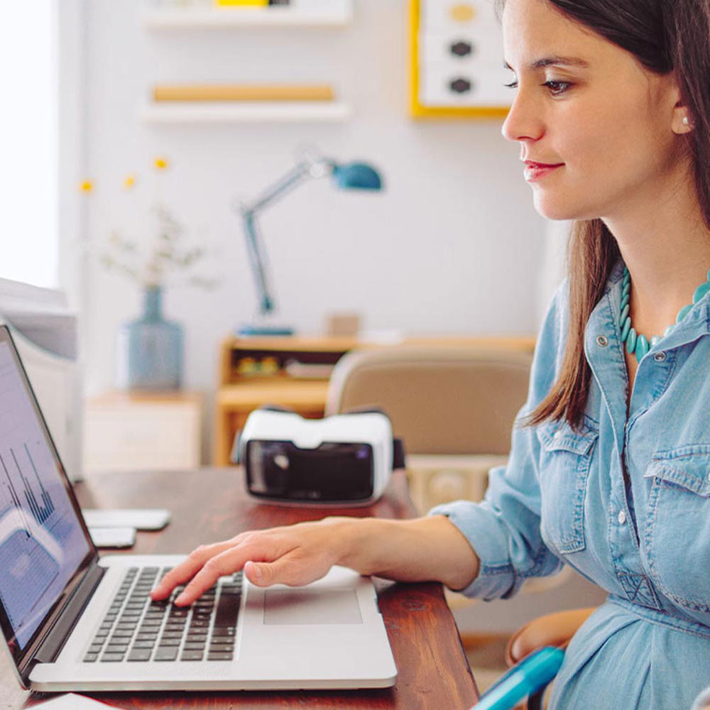 Frau sitzt am Laptop am Schreibtisch